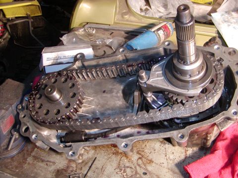 1991 Ford Bronco - Close-up of a disassembled transfer case, revealing internal gears and a chain drive mechanism.