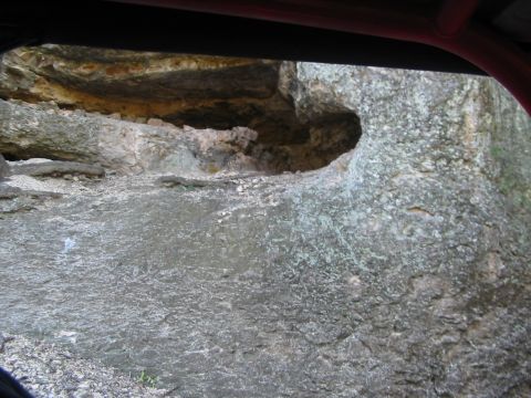 1996 Ford Bronco - View of a cave entrance in a rocky cliff face, seen through the window of a vehicle.