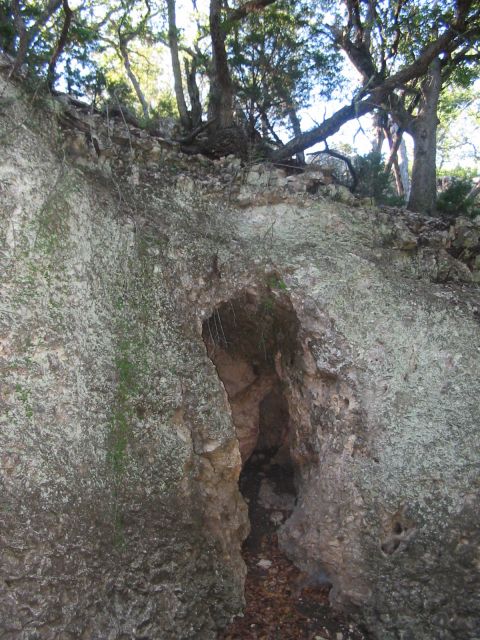 1996 Ford Bronco - A natural rock formation features a dark cave entrance, surrounded by trees and vegetation.