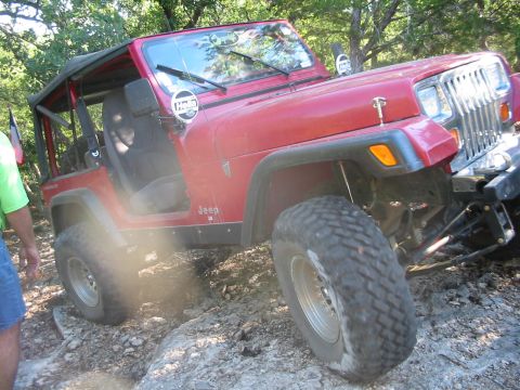1996 Ford Bronco - Red Jeep Wrangler navigating a rocky trail. Grille design suggests a 1991 model year.