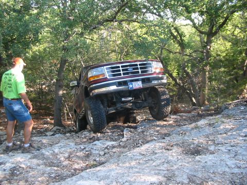 1996 Ford Bronco - A man watches a lifted Ford Bronco navigate a rocky off-road path.