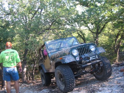 1996 Ford Bronco - A Jeep CJ-7 navigates a rocky, wooded trail during an off-road excursion.