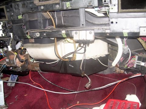 1989 Lincoln Town Car - The heater core assembly is visible with numerous wires and hoses connected, set against a maroon carpeted floor.