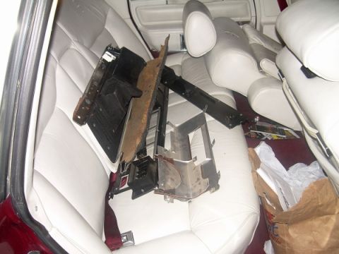 1989 Lincoln Town Car - Disassembled heater core components rest on the white leather interior of a 1989 Lincoln Town Car.