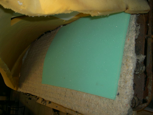 Close-up of green foam padding and yellow fabric from a car seat