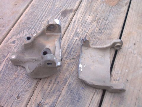 1985 Ford Bronco - Two metal brackets are shown resting on a weathered wooden surface.