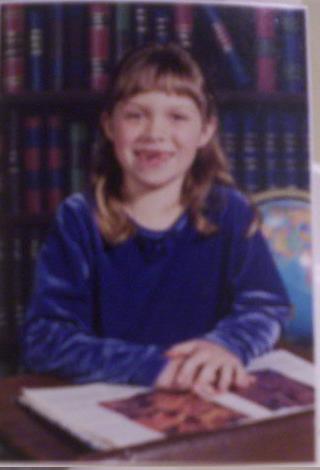 1989 Ford Bronco - A young girl smiles while sitting at a desk in front of a bookshelf.