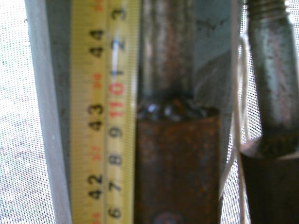 Metal pole with a yellow tape measure showing inches and centimeters, with visible weld marks