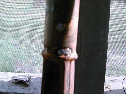 1986 Ford Bronco - A close-up view of a rusted metal pole, showing distinct weld marks and a weathered texture.