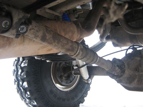 1995 Ford Bronco - A close-up view of the undercarriage reveals the vehicle's drivetrain components and a large tire.