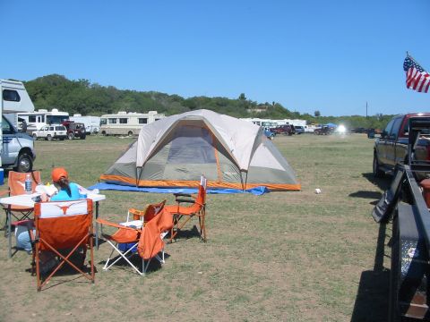 1996 Ford Bronco - Outdoor campsite scene with tents, RVs, and vehicles parked on a grassy field on a sunny day.