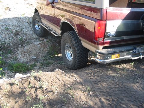 1996 Ford Bronco - This Ford Bronco is navigating a rough, dirt terrain with its off-road tires.