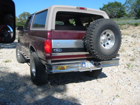 1996 Ford Bronco - Rear view of a maroon Ford Bronco parked outdoors on a gravel surface.