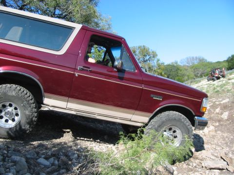 1996 Ford Bronco - A maroon Ford Bronco navigates a rocky trail with another vehicle visible in the background.