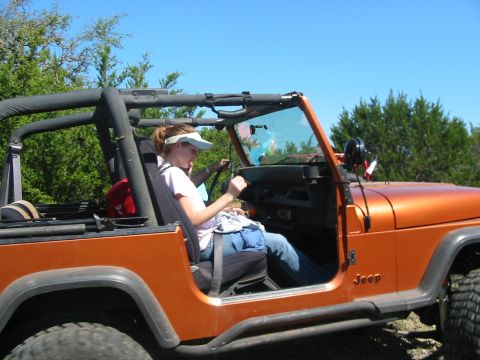 1996 Ford Bronco - A woman drives an orange Jeep Wrangler on a sunny day.