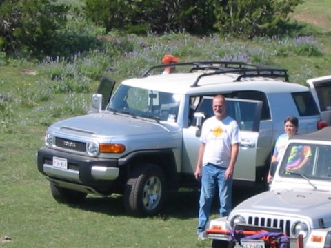 1996 Ford Bronco - A silver Toyota FJ Cruiser is parked in a grassy field with people standing around it.