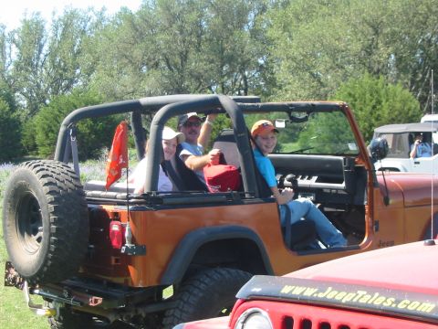 1996 Ford Bronco - Three people ride in an orange Jeep Wrangler, with another Jeep in the background.