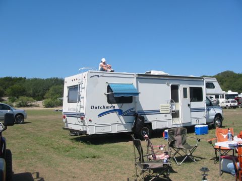 1996 Ford Bronco - An RV is parked on a grassy area under a clear blue sky, with other vehicles visible in the background.