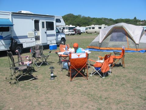 1996 Ford Bronco - A busy campsite scene unfolds with multiple RVs, a large tent, and chairs arranged around a table under a clear blue sky.