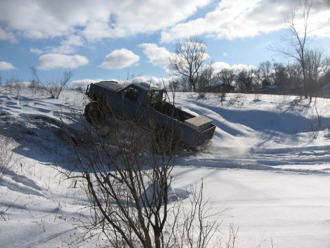 1979 Ford Bronco - Pickup truck navigates a snowy incline on a cloudy day.