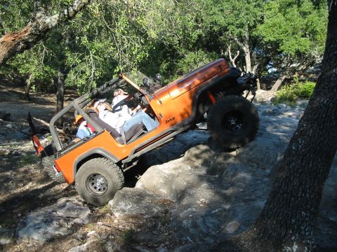 1996 Ford Bronco - A Jeep Wrangler navigates a rocky off-road course, with occupants enjoying the ride.