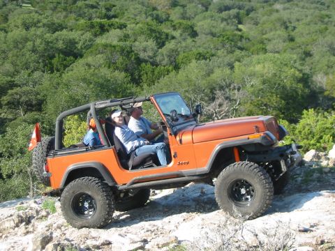 1996 Ford Bronco - A Jeep Wrangler navigates a rocky off-road trail with passengers enjoying the ride.