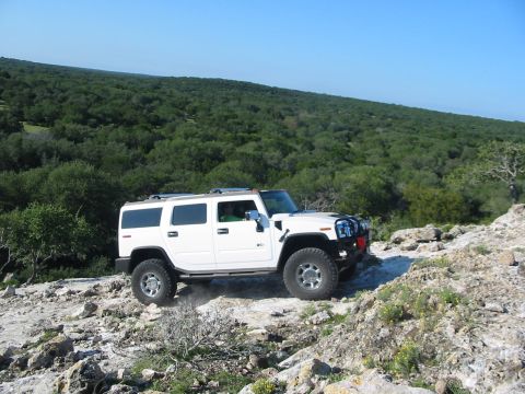 1996 Ford Bronco - White Hummer H2 navigates a challenging rocky terrain under a clear blue sky.