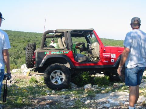 1996 Ford Bronco - A red Jeep Wrangler is parked on a rocky hill with two men standing nearby.