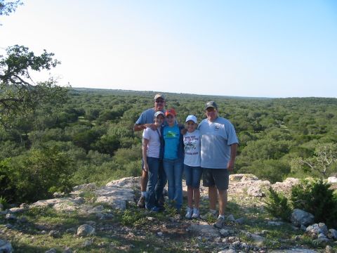 1996 Ford Bronco - A family poses for a photo on a rocky hill overlooking a vast expanse of trees under a clear blue sky.