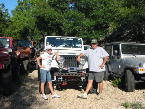 1996 Ford Bronco - A group of Jeeps are parked outdoors with two people posing in front of one.