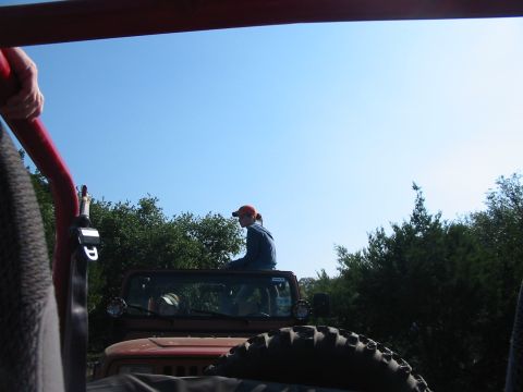 1996 Ford Bronco - A person sits atop a red Jeep Wrangler while another vehicle follows closely behind.