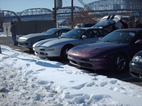 1995 Ford Probe - Several Ford Probes are parked in a snowy lot with a bridge in the background.
