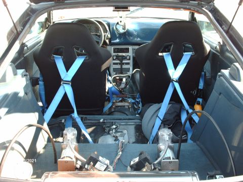 1995 Ford Probe - Interior view of a car with racing seats and aftermarket air compressors installed.