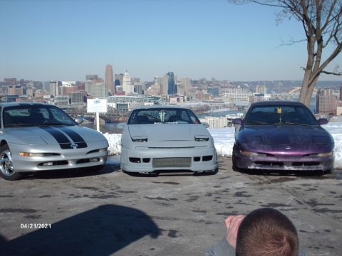 1995 Ford Probe - Three Ford Probes are parked in front of a city skyline on a clear day.