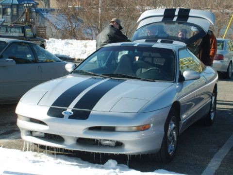 1995 Ford Probe - A silver 1995 Ford Probe with black racing stripes is parked in the snow with its trunk open.