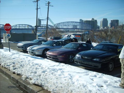 1995 Ford Probe - Several Ford Probes are parked in a line on a snowy day, with a city skyline in the background.