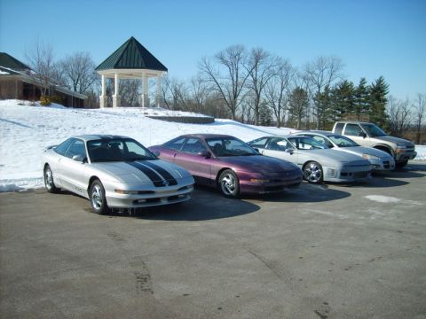 1995 Ford Probe - A line of cars and a truck are parked outside on a sunny, cold day with snow visible on the ground.
