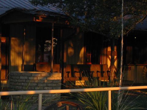 1996 Ford Bronco - A rustic scene a building with a well and benches, illuminated by the setting sun.