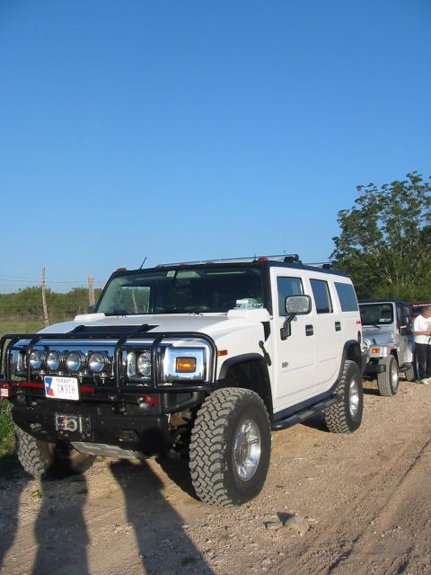 1996 Ford Bronco - A white Hummer H2 SUV is parked on a dirt road with another vehicle behind it.