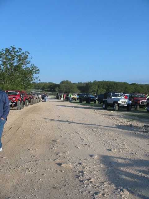 1996 Ford Bronco - A group of Jeeps are parked on a dirt road under a clear blue sky.