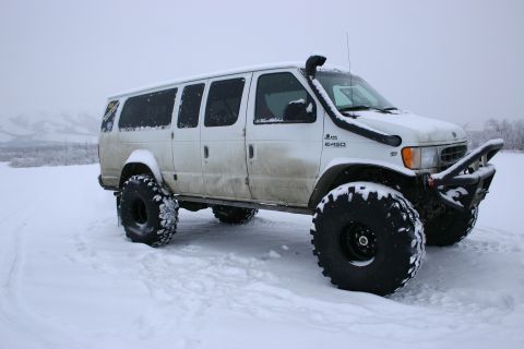 2003 Jeep TJ - A white van modified with oversized tires and a snorkel sits in a snowy landscape.