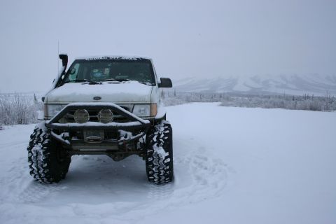 2003 Jeep TJ - A white off-road vehicle sits in a snowy landscape with mountains in the background.
