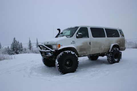 2003 Jeep TJ - A white van, modified for off-road use with oversized tires and a snorkel, sits in a snow-covered landscape.