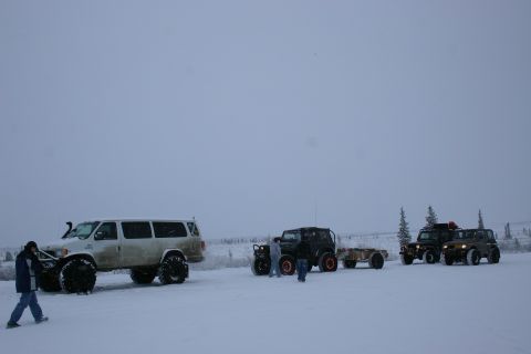 2003 Jeep TJ - Several off-road vehicles are parked in a snowy, overcast landscape with a few scattered trees.