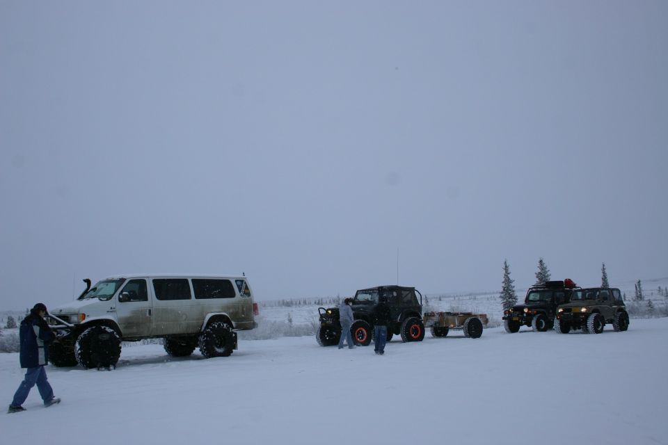 White van with big tires, black Jeep with trailer, and two other Jeeps in a snowy landscape