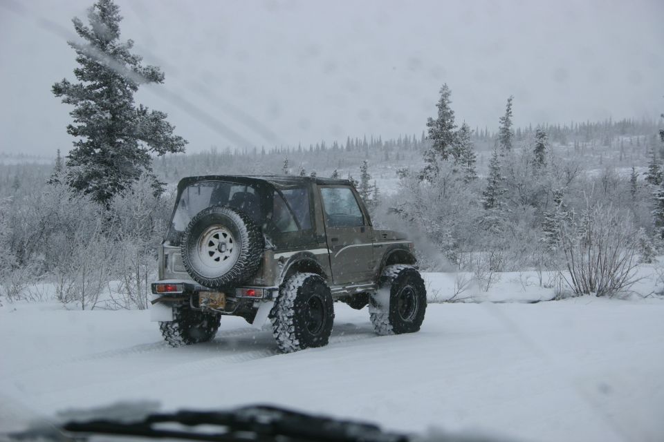 Brown Suzuki Samurai with spare tire on rear door, driving in snow