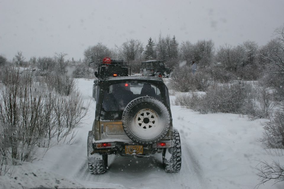 2003 Jeep TJ driving on a snowy trail with other vehicles behind