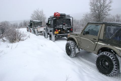 2003 Jeep TJ - Multiple off-road vehicles navigate a snowy trail during winter conditions that appear to be wintery.
