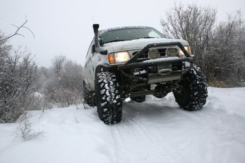 2003 Jeep TJ - A white off-road SUV navigates a snowy trail with its snorkel visible.
