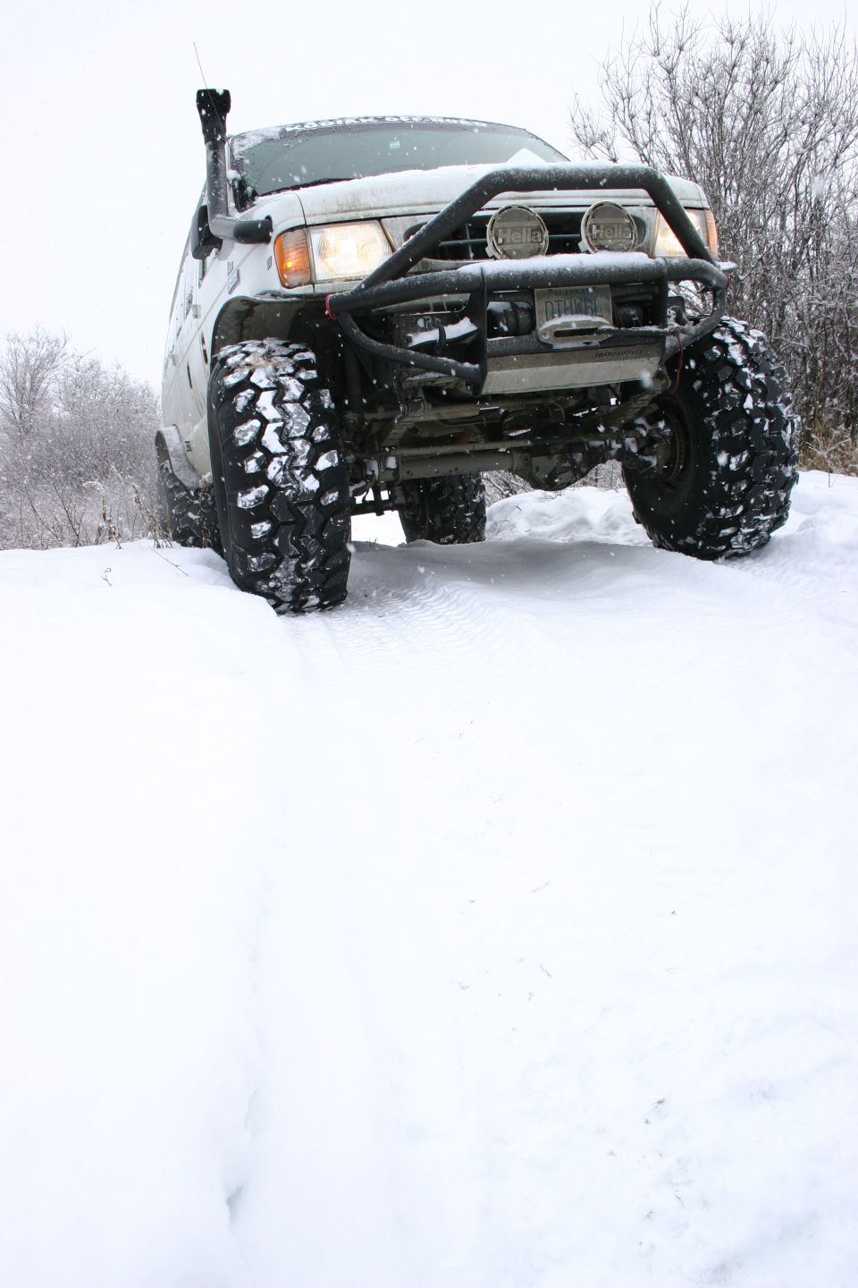 White SUV with snorkel and bull bar driving in snow
